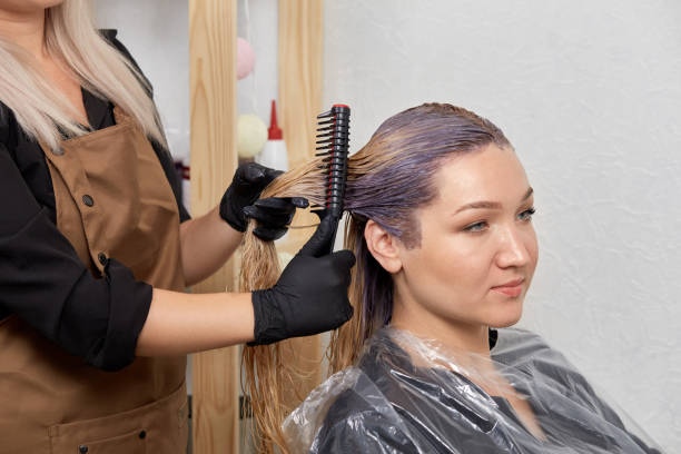 ein weiblicher barbier trägt einen aufheller auf den haarkäfig auf. - lightener stock-fotos und bilder