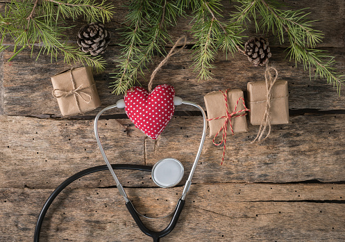Medical Christmas banner with gift present box, stethoscope and Christmas tree on wood background.