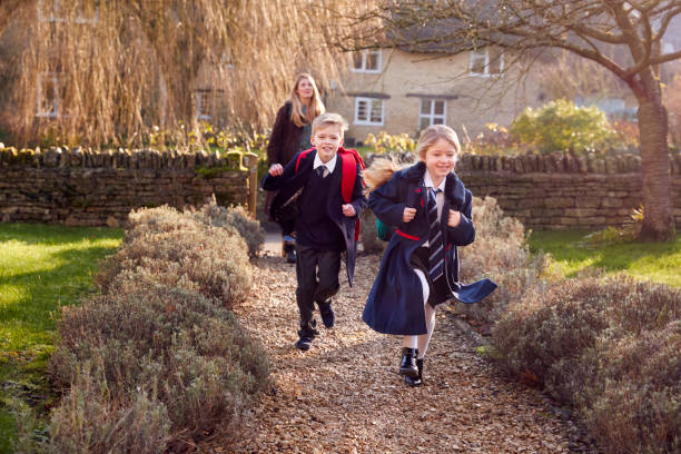 istock Mother Returning Home From School With Children Wearing School Uniform Running Down Path 1289912905