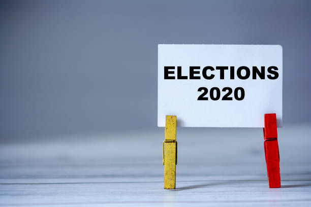 istock Reminder sticky note with clothes pin on table. Sticky note with inscription ELECTIONS 2020. President elections in USA concept 1289913018