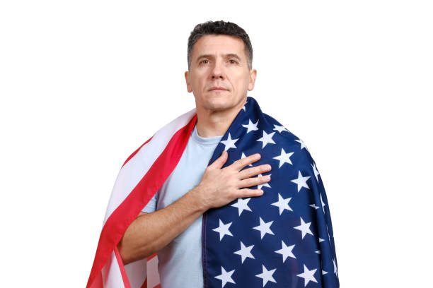 istock Handsome middle-aged man covered with American flag puts hand on his heart 1289914200