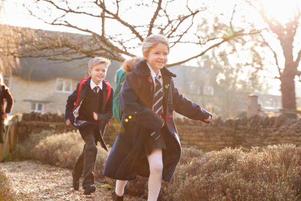 istock Children Wearing School Uniform  Returning Home From School Running Down Path 1289914969