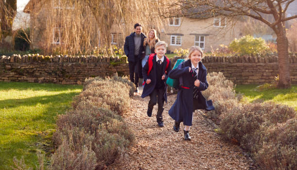 istock Parents Returning Home From School With Children Wearing School Uniform Running Down Path 1289915999