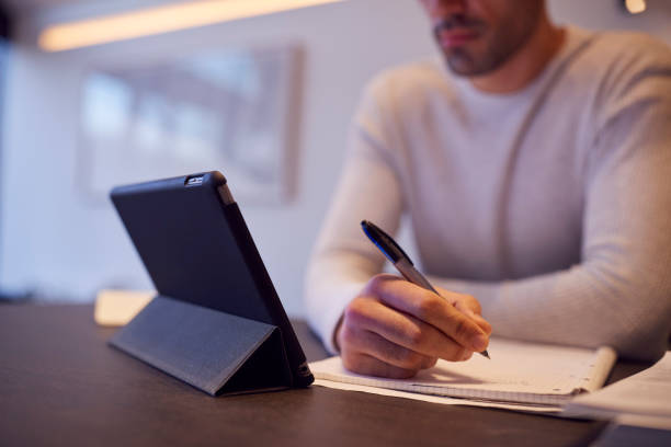 istock Close Up Of Man In Kitchen Working Or Studying From Home Using Digital Tablet 1289916952