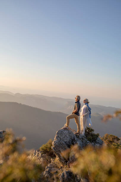 maduras caminatas de pareja a lo largo de la soleada cresta de la montaña en la mañana - couple mature adult europe travel fotografías e imágenes de stock