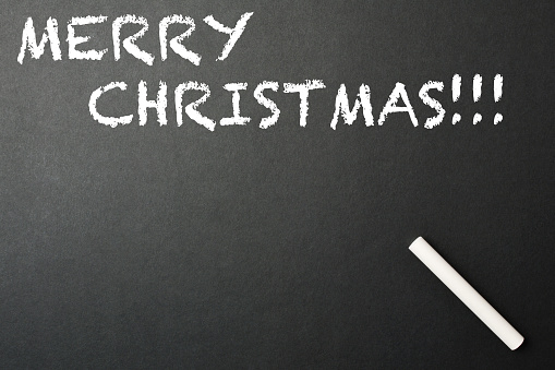 Merry Christmas written on the blackboard with a white chalk and copy space