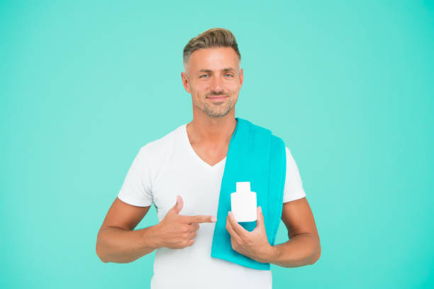 handsome man with pill jar. guy presenting gel bottle. male beauty and health. daily morning routine. unshaven man has stylish hair or haircut. ready to take shower with towel - vibrant color healthcare and medicine healthy lifestyle vitamin pill imagens e fotografias de stock