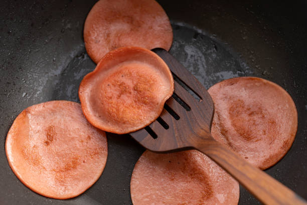 frying bologna closeup frying pork bologna in black pan with small amount of cooking oil baloney stock pictures, royalty-free photos & images