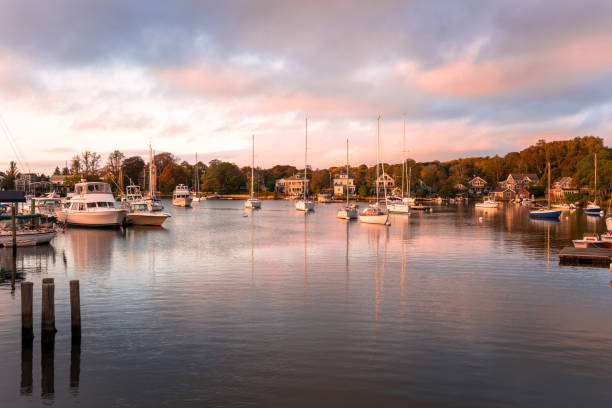 barche in un bellissimo porto circondato da boschi al tramonto. riflessione in acqua. - cape cod foto e immagini stock