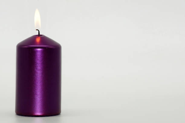 istock Purple candle burning on bright background exposed 1289922278