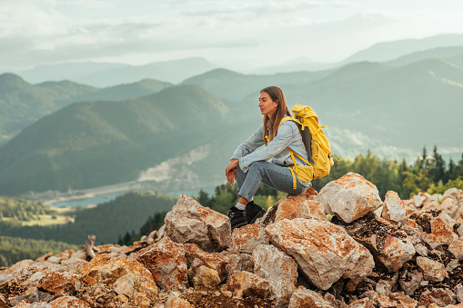 Young female with backpacker taking a break while hiking in the mountain