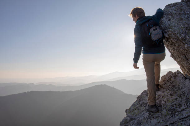 istock Hiker scrambles up mountain ridge in the morning 1289923609