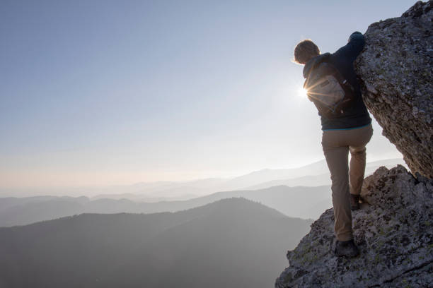 istock Hiker scrambles up mountain ridge in the morning 1289923866