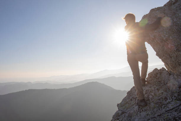 istock Hiker scrambles up mountain ridge in the morning 1289923927