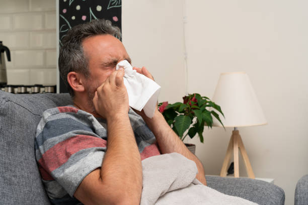 istock Adult man with flu symptoms blowing nose using napkin 1289924443