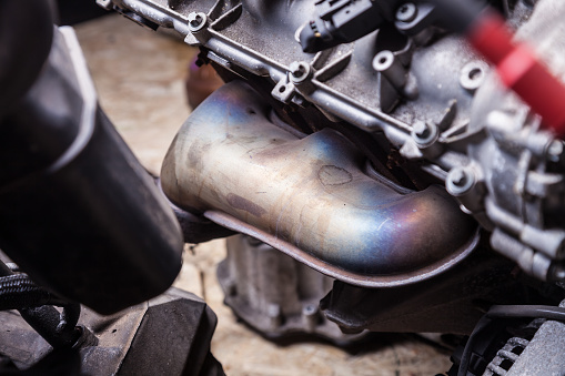 Close-up of an engine exhaust pipe repair in a garage or car service center for further sale at an auto-analysis. Background for car service or men's magazine.