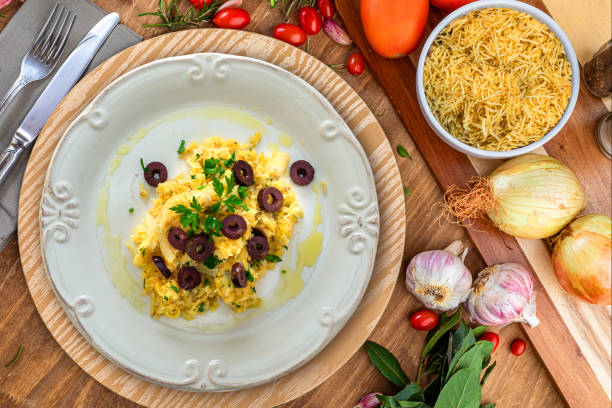 istock A typical Portuguese dish of shredded cod, with potato straw, mixed egg and dark olives. On a wooden table, with garlic, onion, parsley and others. Top view. Space for text. 1289927662