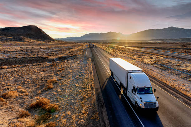 camion semi-remorque blanc se dirigeant vers le bas d’une route à quatre voies au crépuscule - fret photos et images de collection