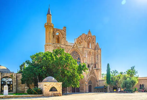 Lala Mustafa Pasha Camii Mosque or Old Cathedral of Saint Nicholas medieval building with minaret in Famagusta historical city centre, clear blue sky in sunny day, Cyprus