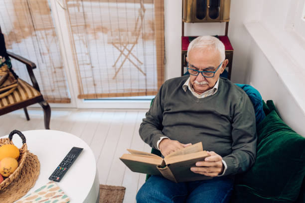 istock Senior man relaxing on the sofa and reading a novel 1289929086