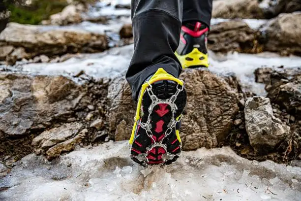 Shoes with yellow crampons on the mountain trail in winter, climbing, adventure.