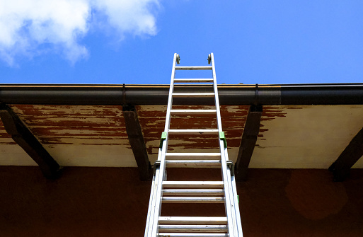 Metal ladder to sky across the building and rooftop close-up. Stairway to heaven