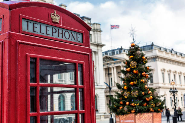 rote telefonzelle und weihnachtsbaum mit großen orangefarbenen globus dekoration in london - architecture international landmark famous place decoration stock-fotos und bilder