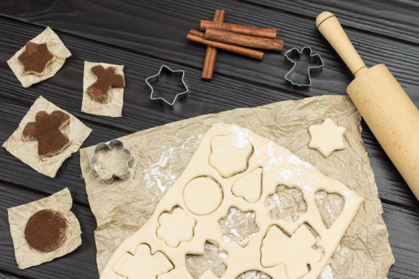 istock Cutting shaped cookies by mold. Fir branches, molds, cinnamon sticks and rolling pin 1289934890