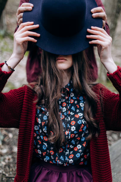 istock A girl with long hair covers her face with a hat. 1289935788