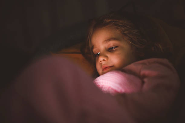 Headshot of little girl afraid and hiding behind her bed sheets