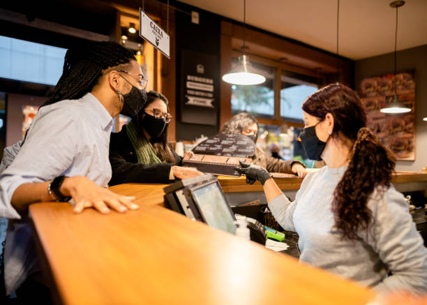 istock Couple ordering in a restaurant counter using facial mask 1289936935