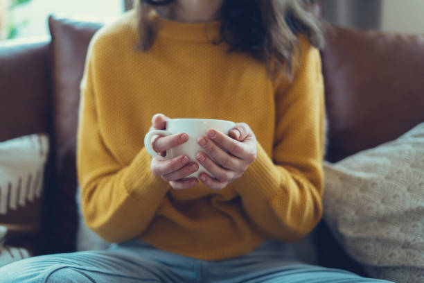 женщина, держащая чашку с напитком в руках - drinking tea cup drink стоковые фото и изображения