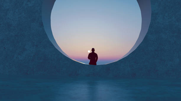 istock Man sits in a round window looking at the sun that sets in the horizon 1289937791