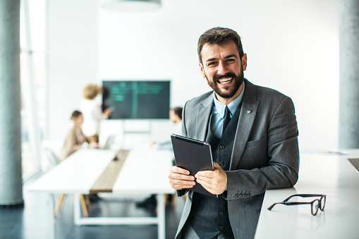 handsome businessman using a digital tablet while standing in a modern office