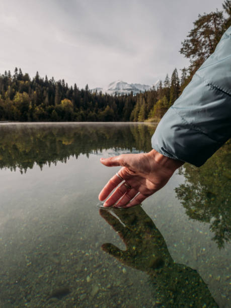 istock Woman's hand touches surface of alpine lake 1289940370