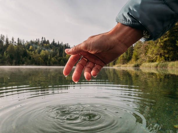istock Woman's hand touches surface of alpine lake 1289940739