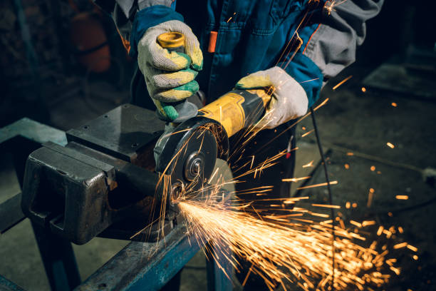 istock Locksmith in special clothes and goggles works in production. Metal processing with angle grinder. Sparks in metalworking 1289940832