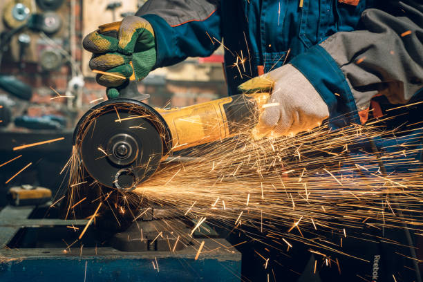 istock Locksmith in special clothes and goggles works in production. Metal processing with angle grinder. Sparks in metalworking 1289940976