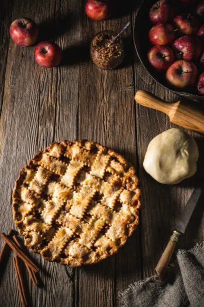 American apple pie on rustic wooden table homemade with ingredients rolling pin and dough