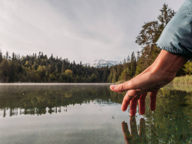 istock Woman's hand touches surface of alpine lake 1289942252
