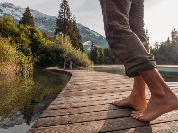 istock Low angle view of man walking barefoot across dock at sunrise 1289942624
