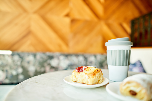 Close-up of delicious pastries and a reusable takeaway coffee cup sitting on a table in a cafe