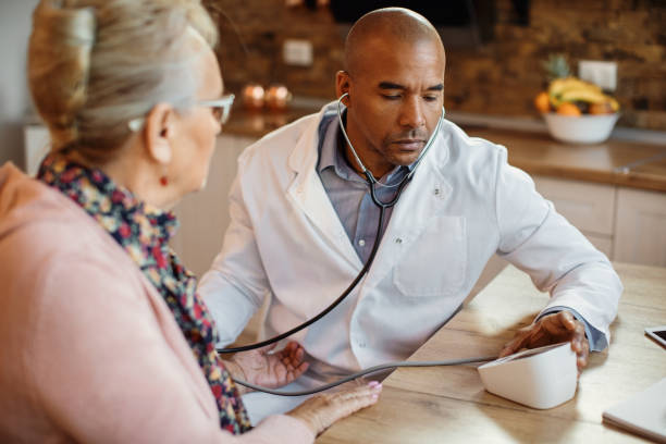 istock Black general practitioner measuring mature woman's blood pressure at nursing home. 1289943781