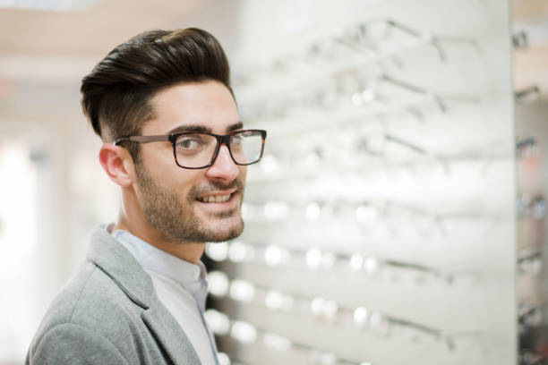 istock Man looking some glasses in optical store, trying on lenses and looking at camera 1289945092