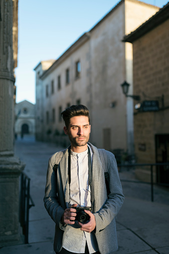 Young tourist man taking pictures with sunset light, Baeza, Spain.