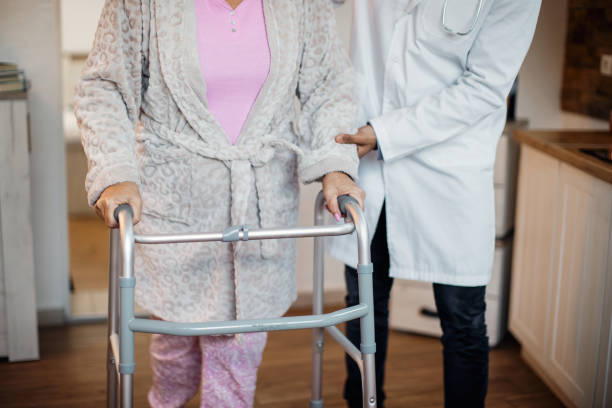 istock Unrecognizable elderly woman using mobility walker with help of a doctor at nursing home. 1289945195