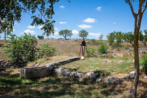 Old stone made water tank  with manual pump in an authentic landscape of Murgia. Apulia, Italy