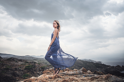 Woman in blue dress at the rocky coast