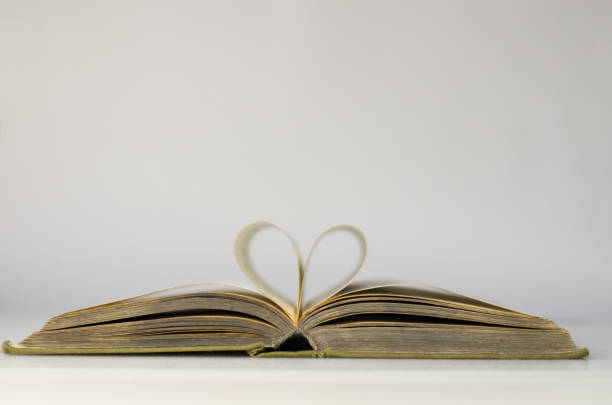 An old open book. I love reading. Close-up of book pages folded into a heart shape. Close-up of book pages folded into a heart shape. Love of reading. book heart shape valentines day copy space stock pictures, royalty-free photos & images