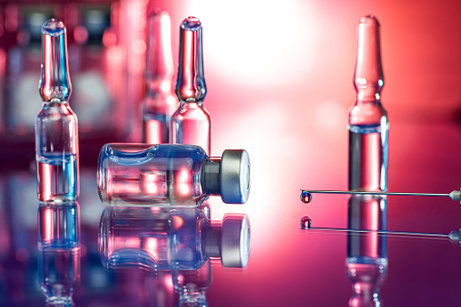 Close up shot of syringe in laboratory - Flu shot and covid-19 vaccine - stock photo with reflections of light and glass